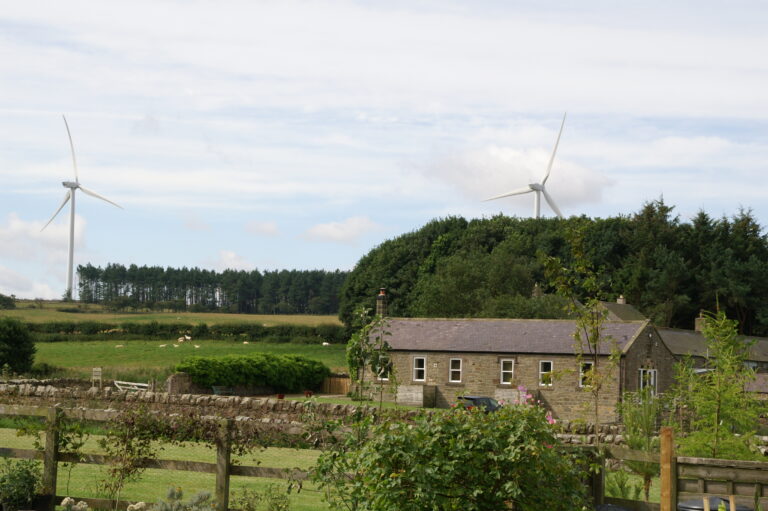 Rural house, agricultural fields, woodland and wind turbines.